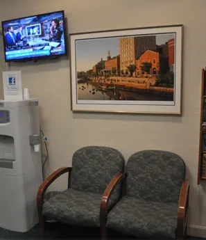 A corner of the waiting room with a television, a water cooler and a framed print of Providence.