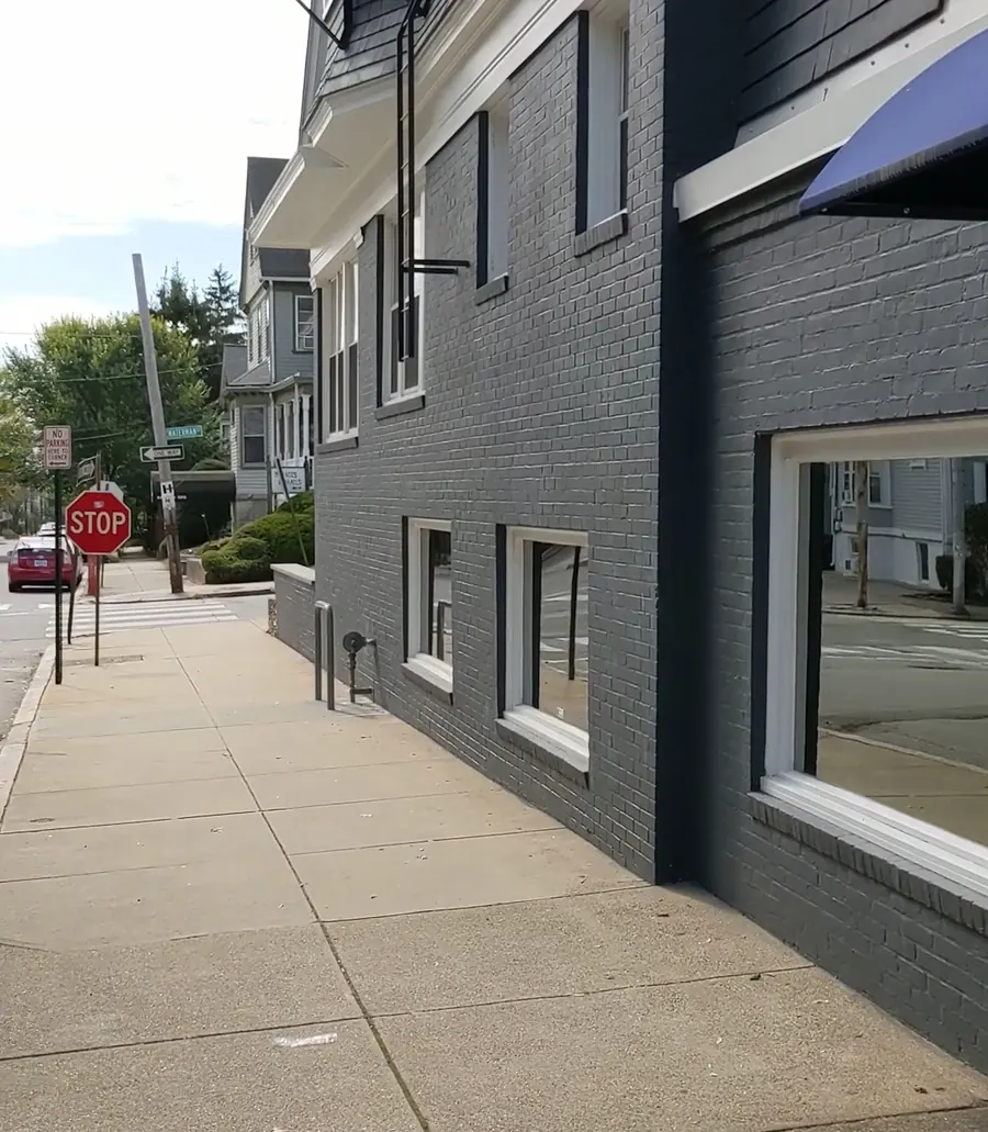 The side of the practice building along the sidewalk, with its black awning and wide windows.